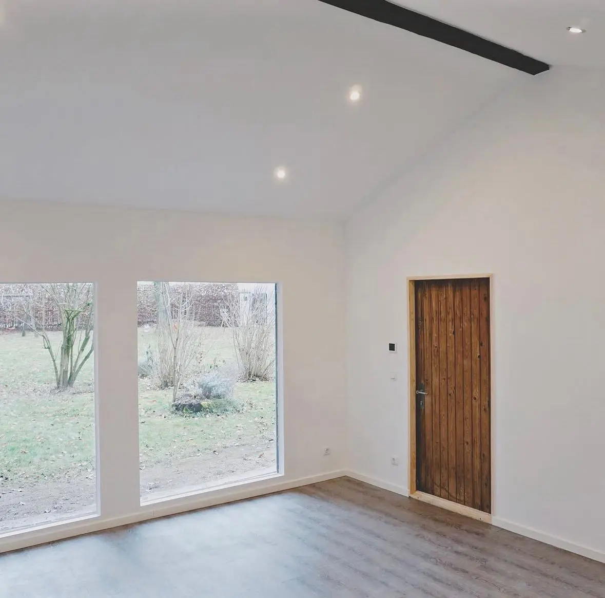 Refurbished living room in a house with new flooring and a wooden door